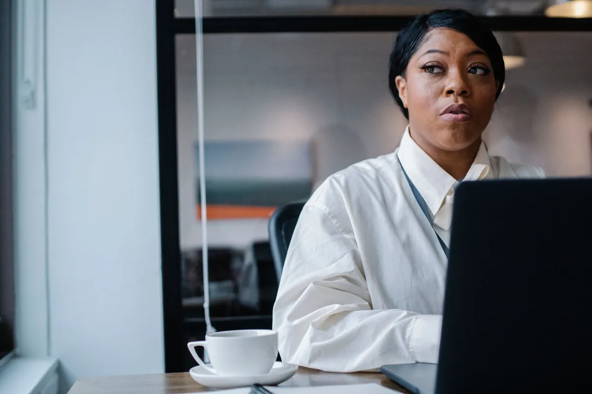 Professional in a crisp white shirt reviewing privacy settings on a laptop with coffee nearby