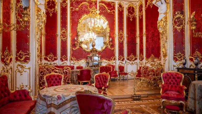 Crimson and gold rococo salon with a crystal chandelier and velvet chairs