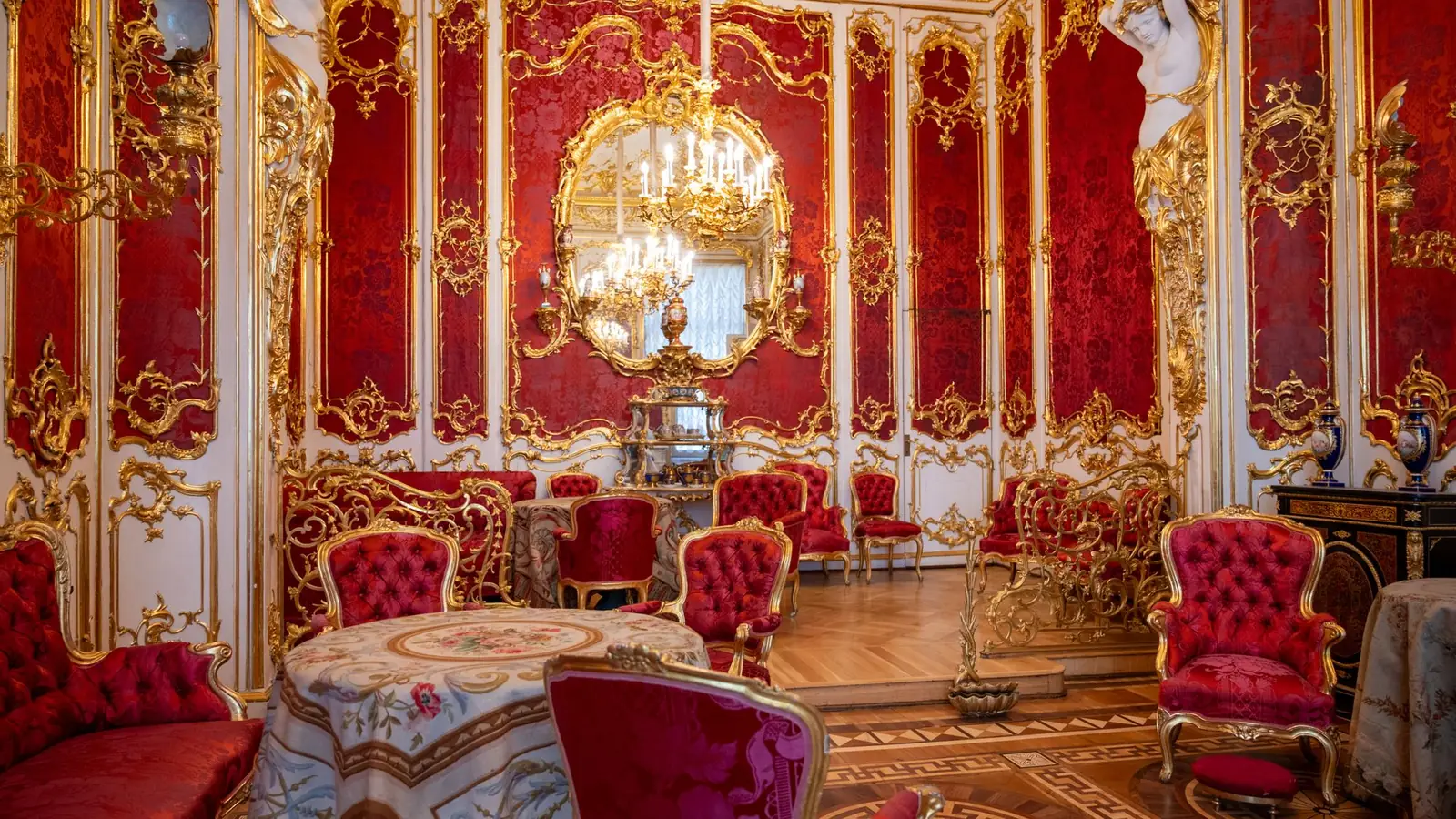 Crimson and gold rococo salon with a crystal chandelier and velvet chairs