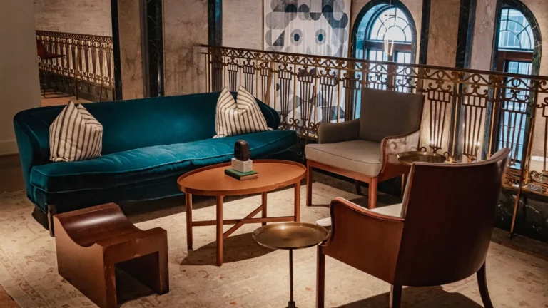 Lounge with a teal velvet sofa, wrought-iron balcony and tall arched windows