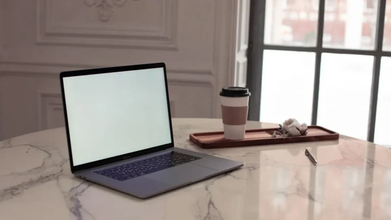 Laptop on a marble table beside tall windows in an elegant room
