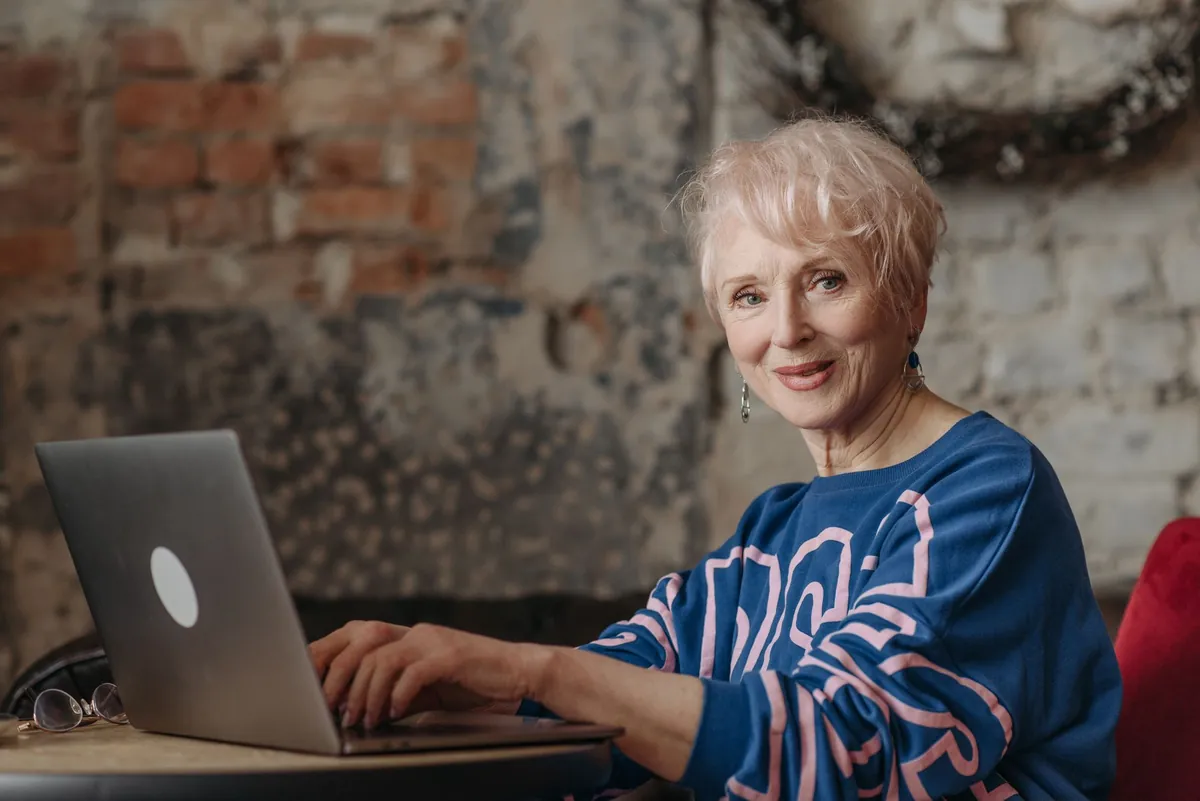 Professional working on a laptop in a home office with a brick wall, researching answers online