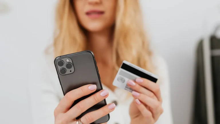 Woman holding a smartphone and a payment card while signing up for a membership online