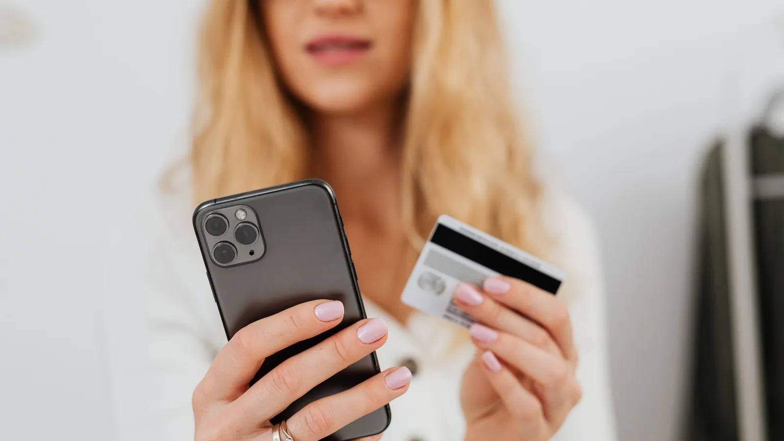 Woman holding a smartphone and a payment card while signing up for a membership online