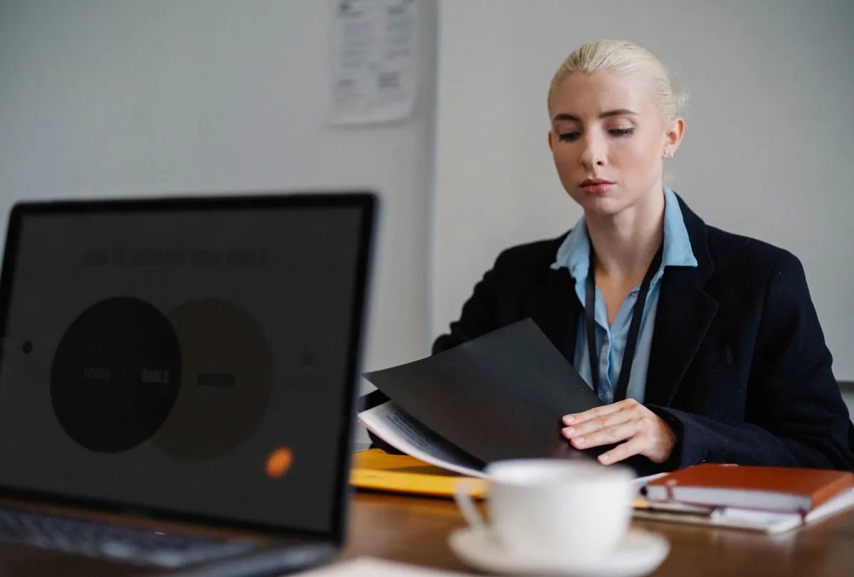 Focused woman in formal attire working on a laptop at a white desk