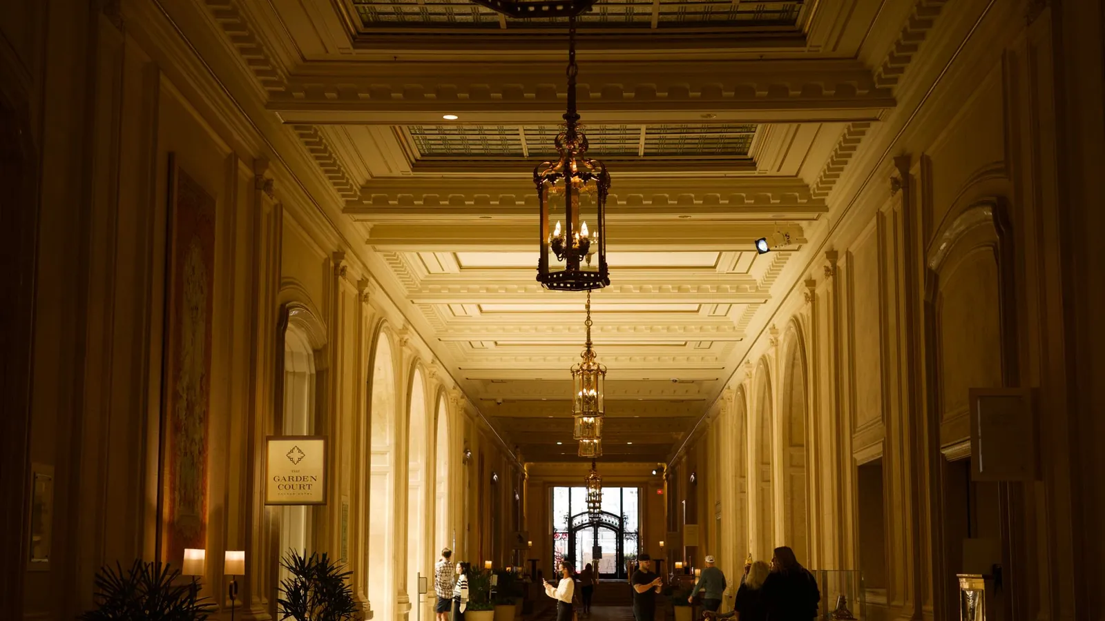 Long gilded corridor lit by hanging bronze lanterns