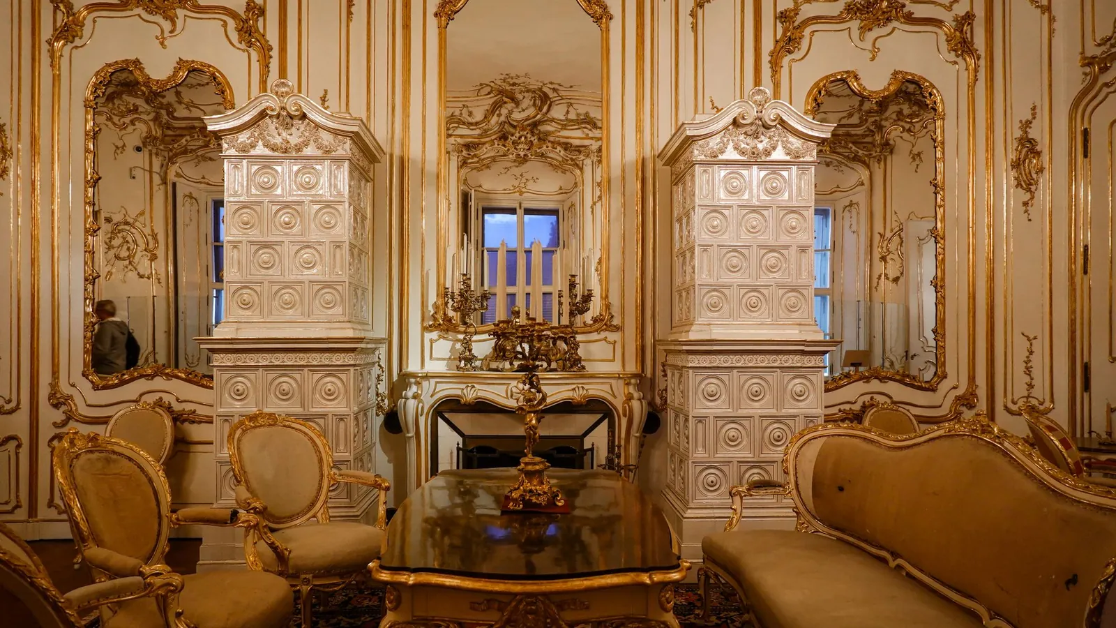 Gilded salon with carved gold paneling and upholstered seating