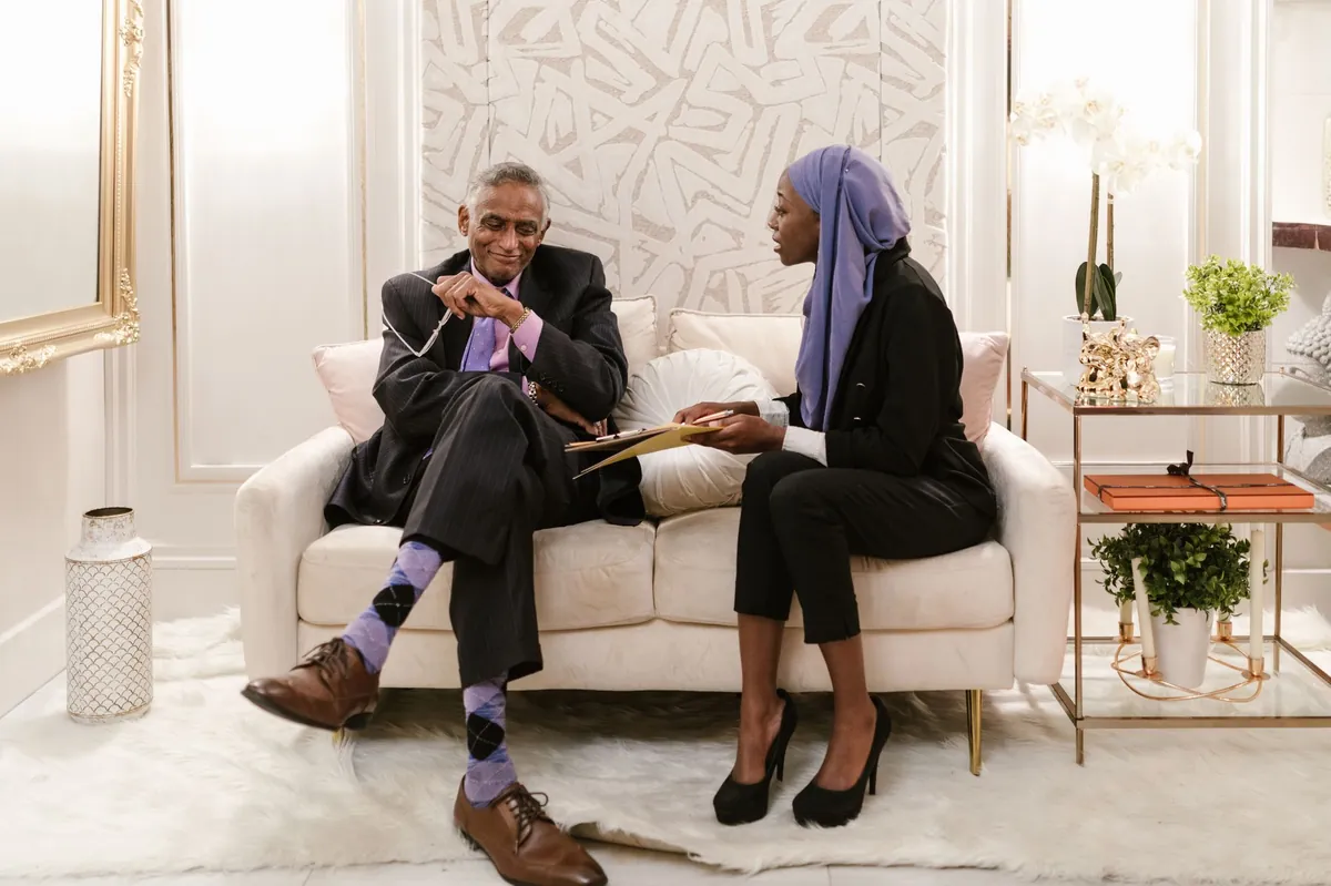 Two professionals in conversation on a sofa in an elegant consultation room