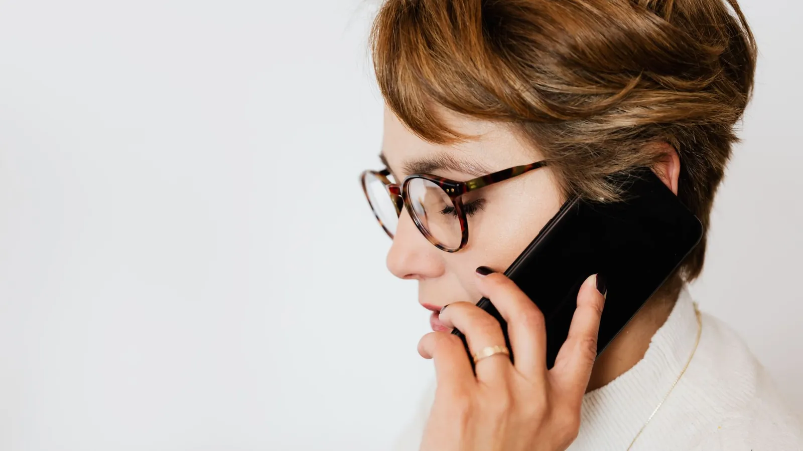 Office manager in eyeglasses on a phone call against a white background