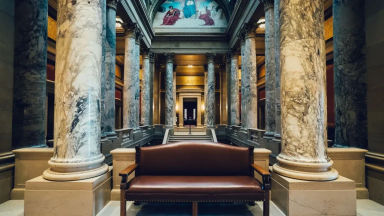 Grand marble hall with tall columns and a leather bench