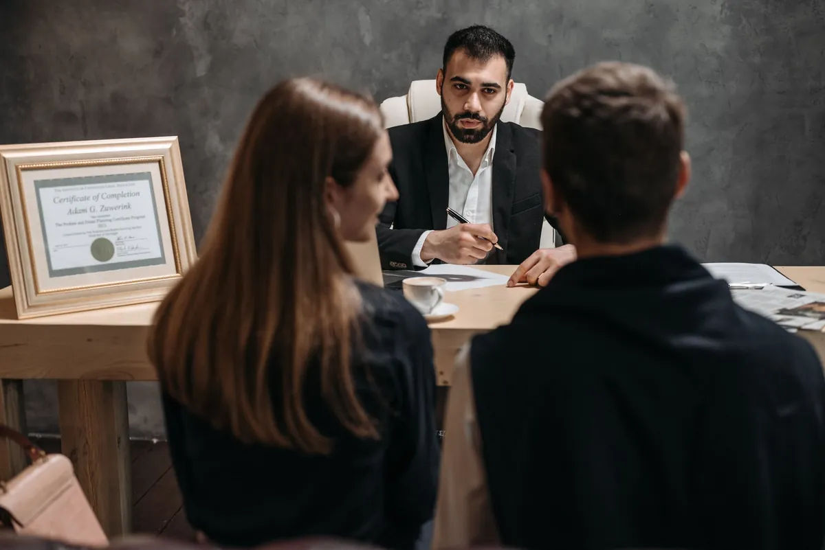 Consultation across a desk with a framed certificate in a dark office