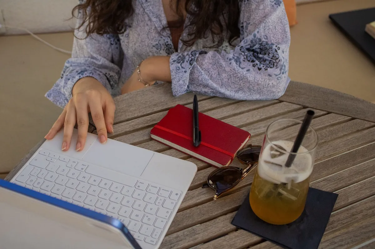 Laptop, notebook and drink on an outdoor cafe table during research work