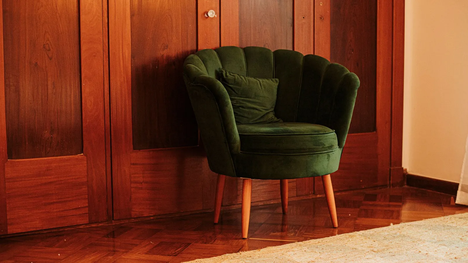 Green velvet armchair against warm wood paneling in a private office