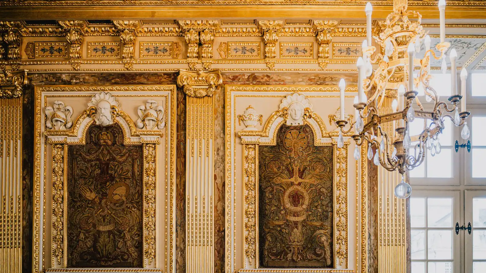 Gold-paneled salon with carved reliefs and a crystal chandelier