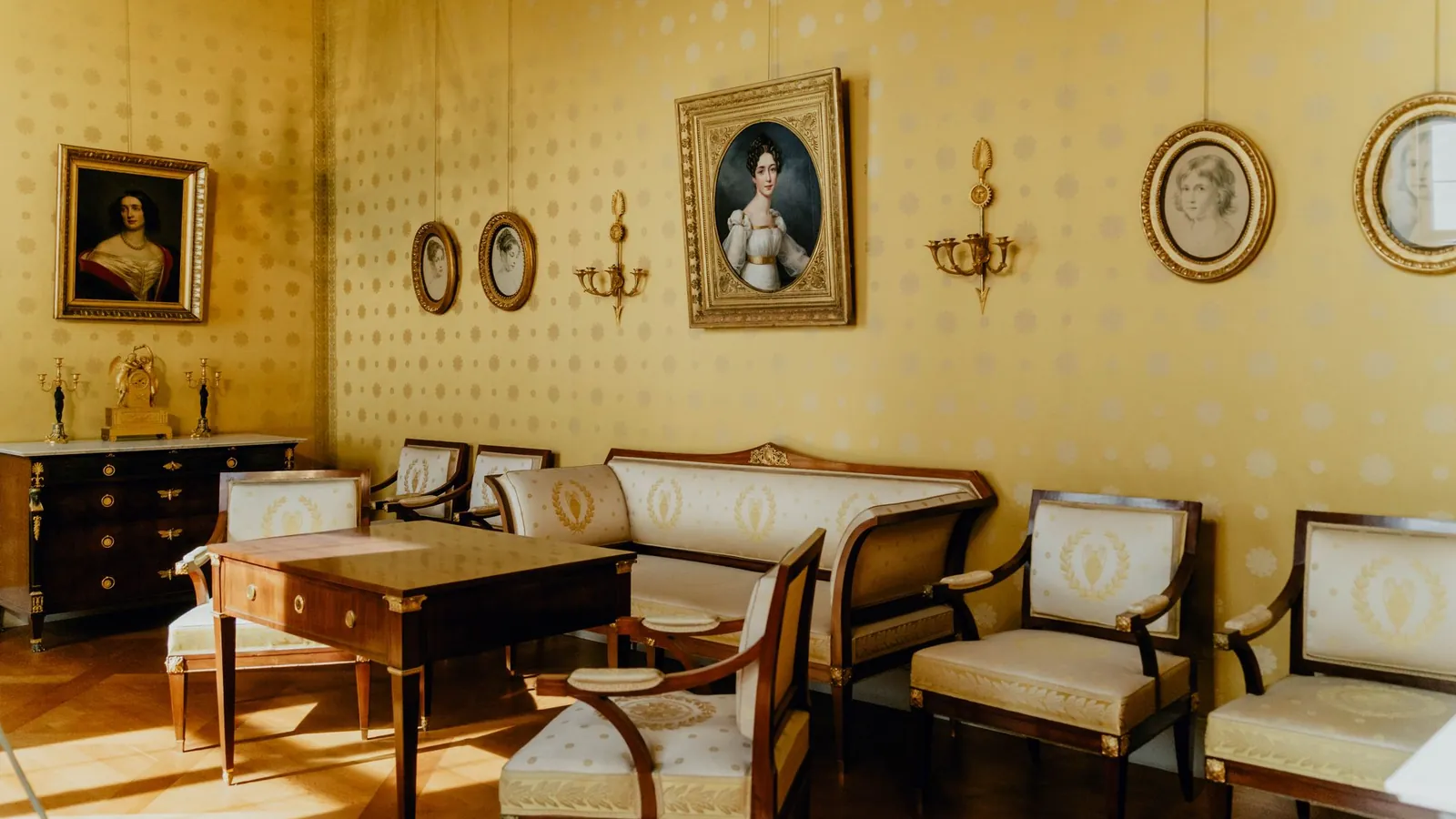 Classic salon with gilded frames, upholstered chairs and a writing desk