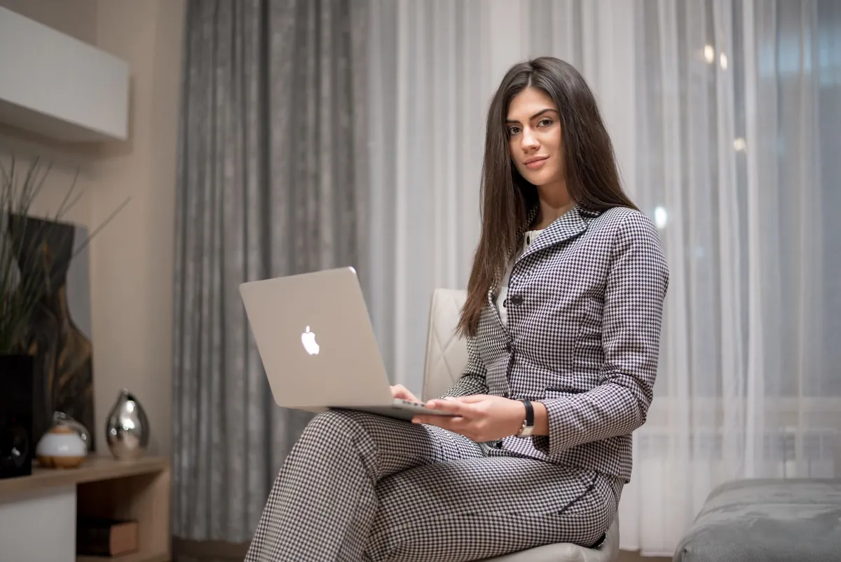 Professional in a gray suit working on a laptop in a softly lit room