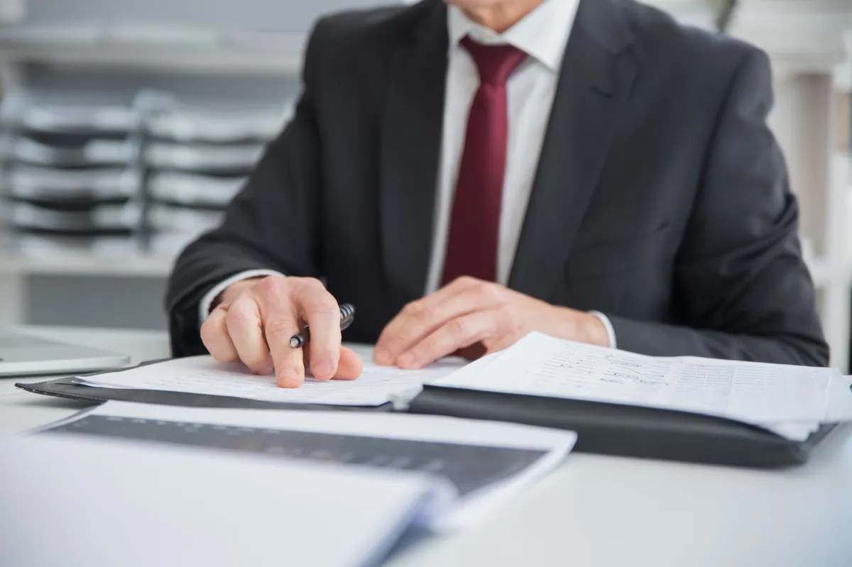 Executive in a suit reviewing printed documents at a desk