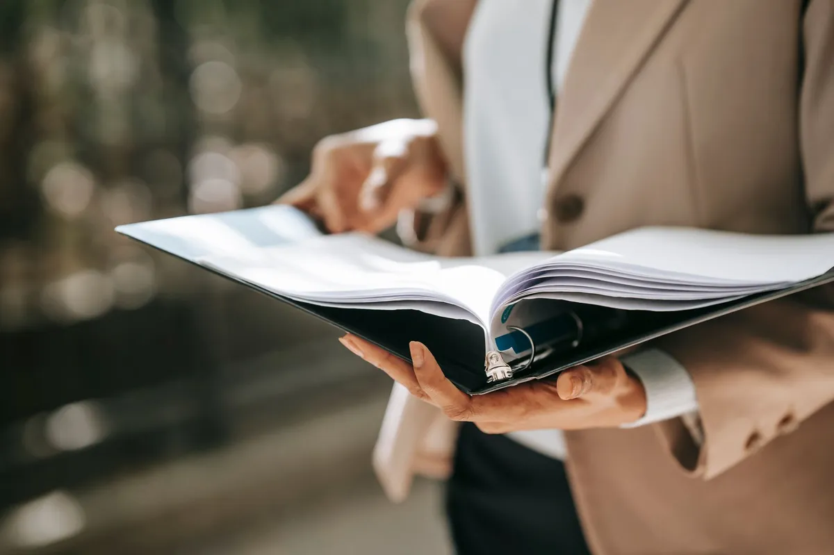 Close view of hands holding an open binder during a document review