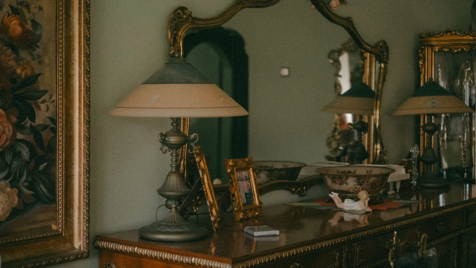 Antique sideboard with gilded mirrors, porcelain bowls and fabric-shaded lamps
