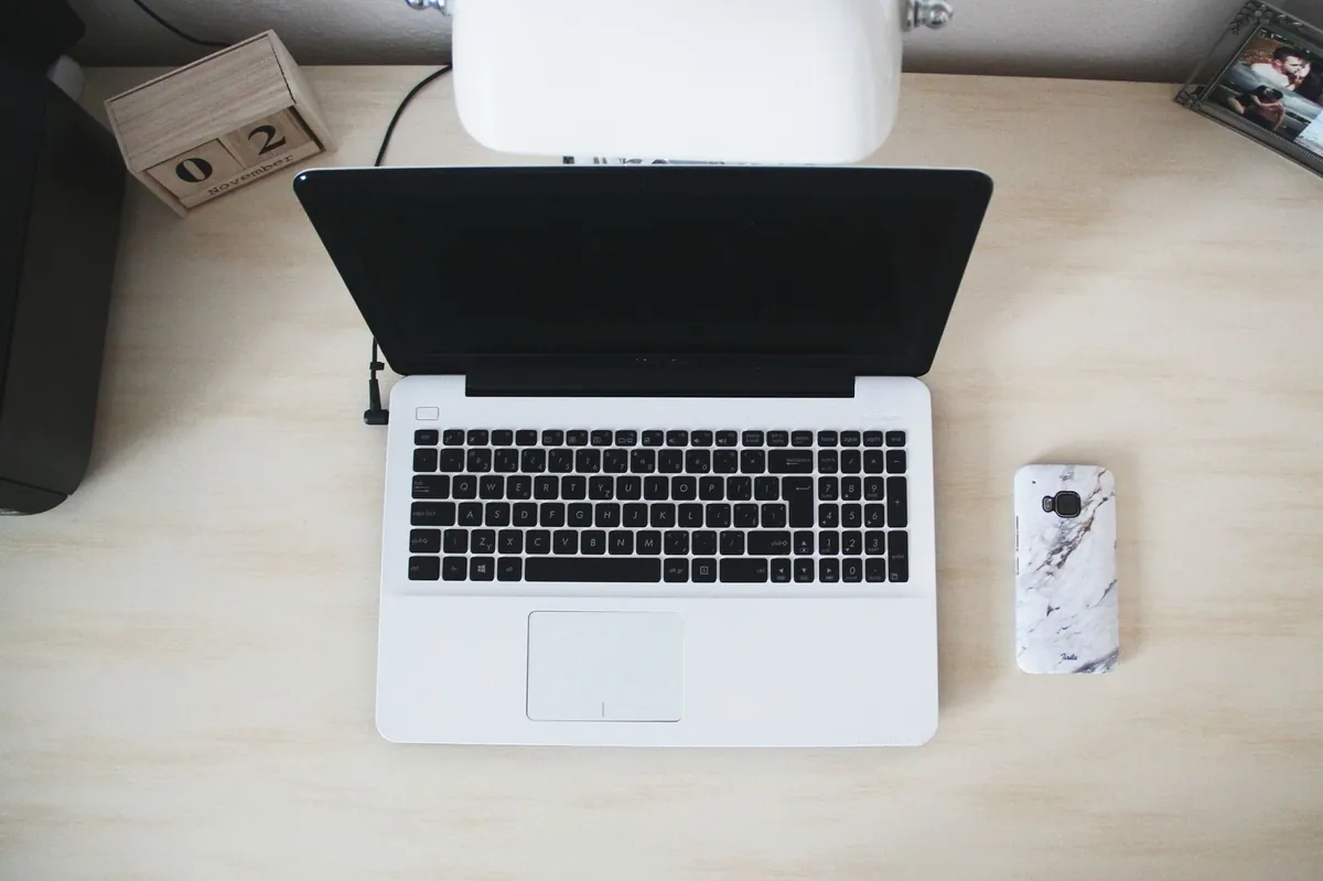 Top view of a minimalist workspace with laptop, smartphone and desk accessories