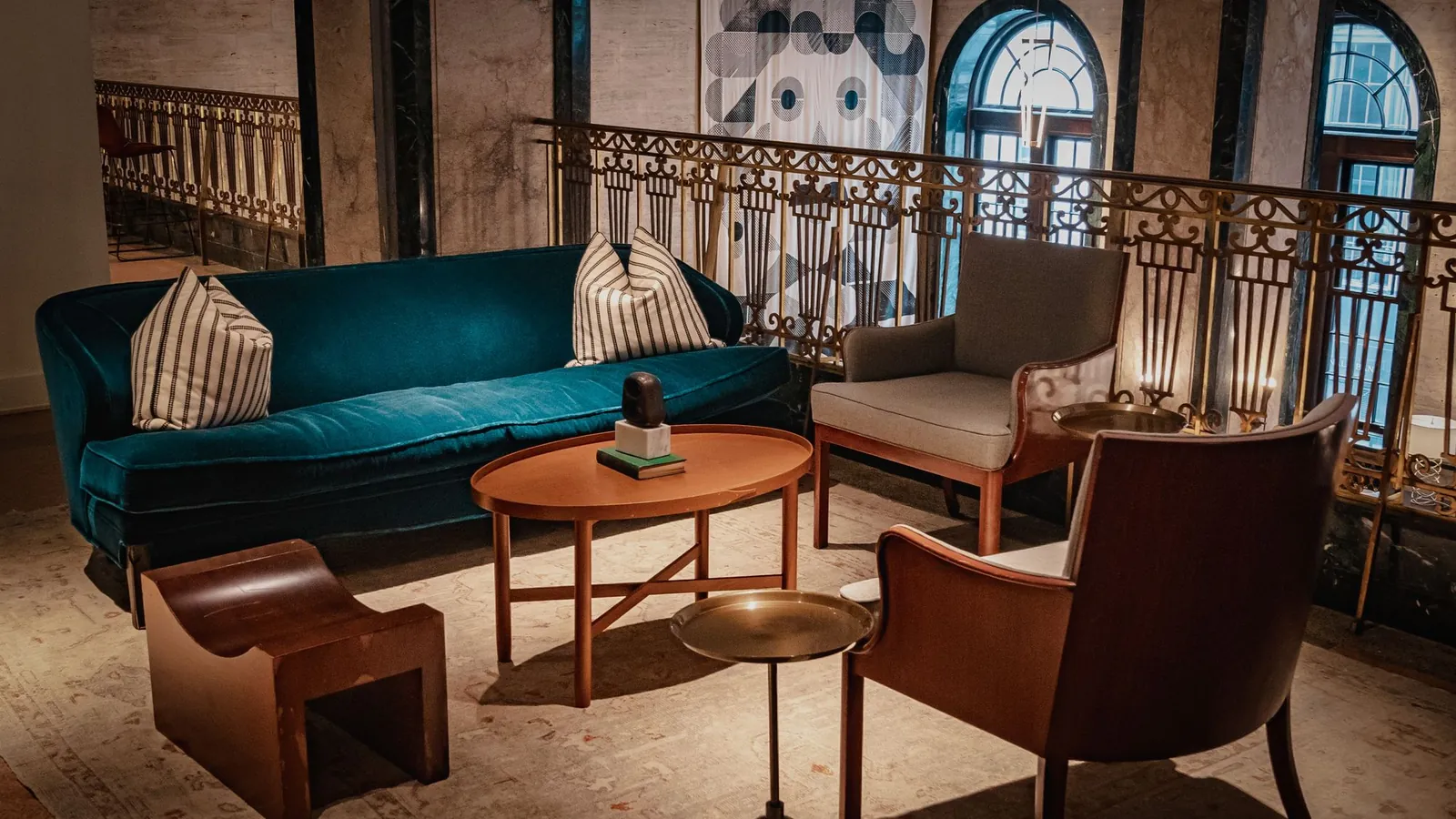 Lounge with a teal sofa, leather chairs and arched windows