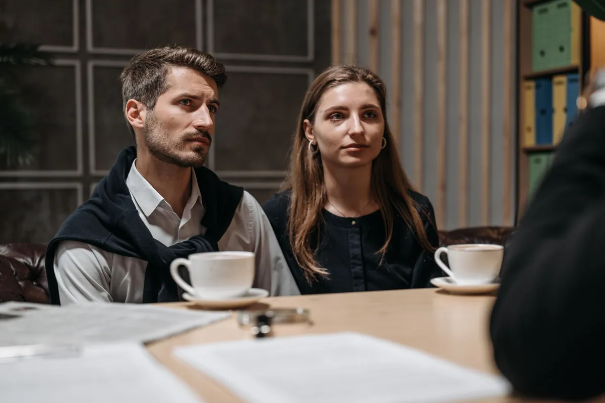 Two colleagues at a cafe table with coffee, listening during a planning talk