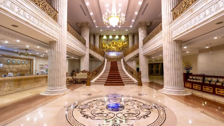 Grand marble lobby with columns, an inlaid floor and a sweeping staircase