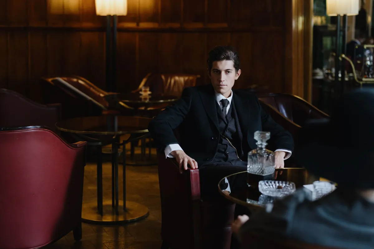 Man in a dark suit seated in an elegant low-lit lounge