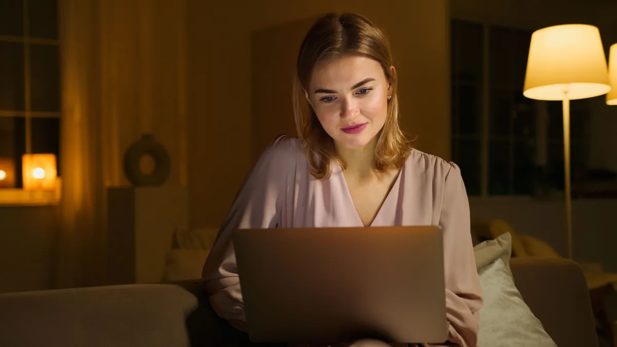 Professional reviewing a laptop in a warmly lit lounge in the evening