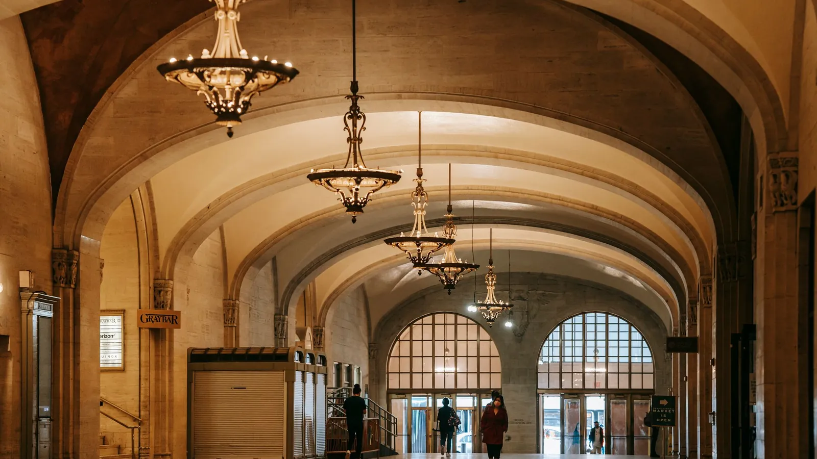 Vaulted arcade with a row of brass chandeliers and arched windows