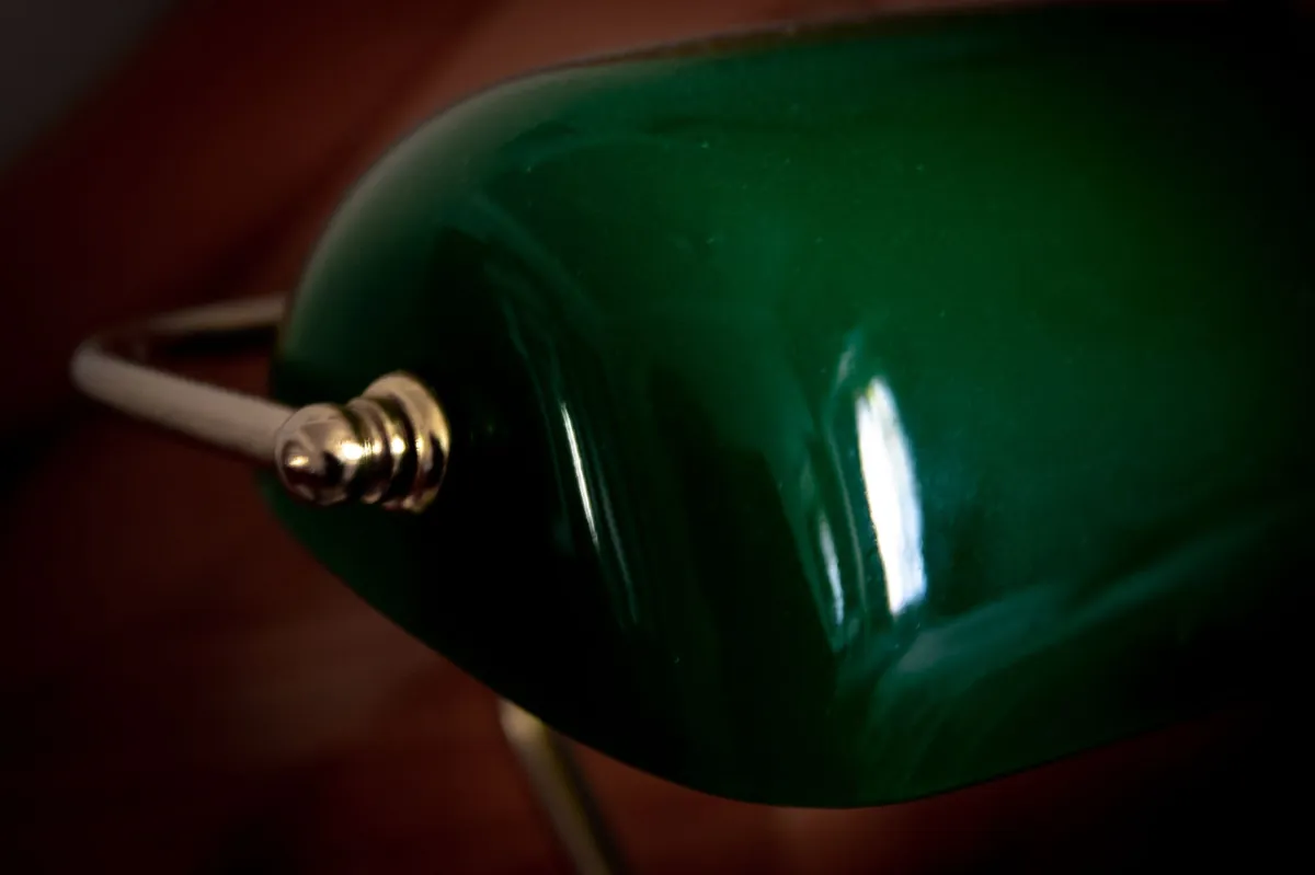 Close view of a green glass banker lamp shade with brass fittings