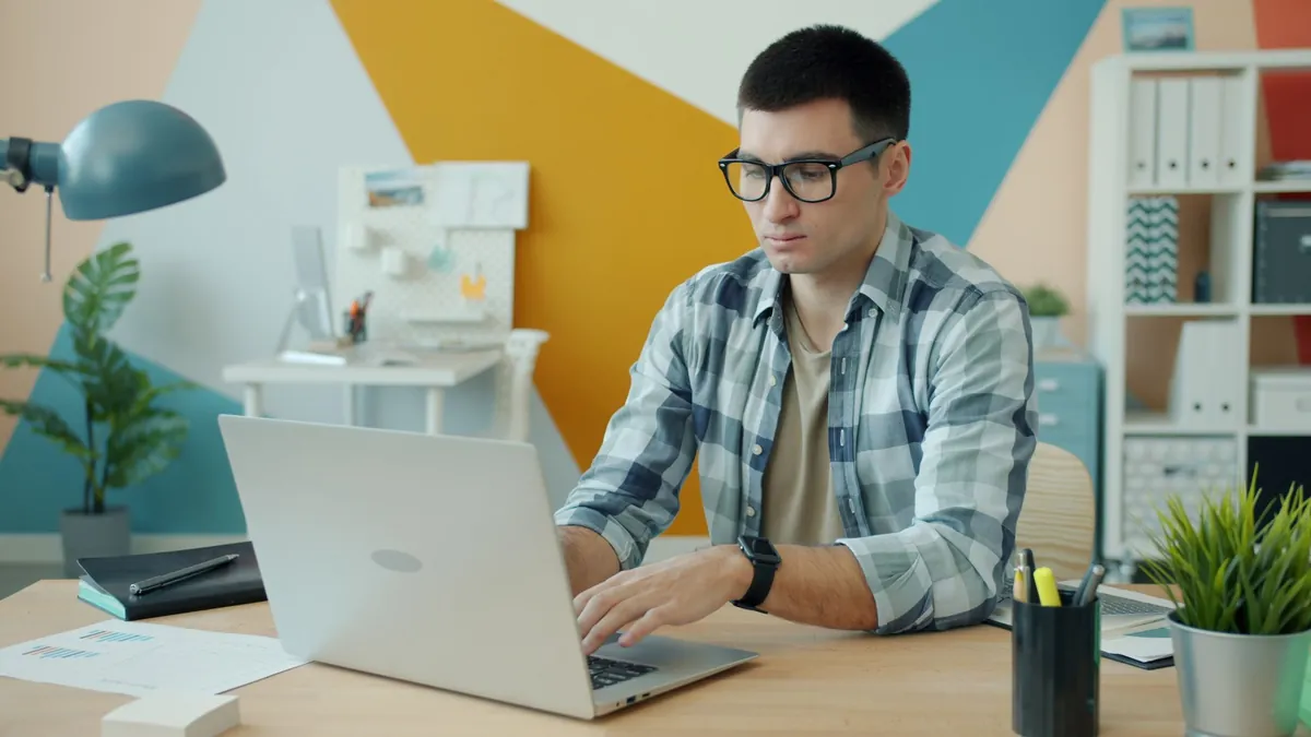 Marketing strategist in glasses reviewing search results on a laptop in a stylish modern office