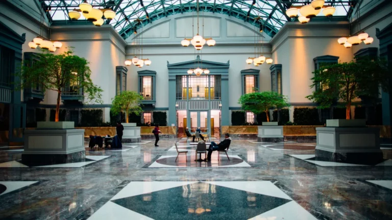 Glass-roofed hall with a marble floor and potted palms
