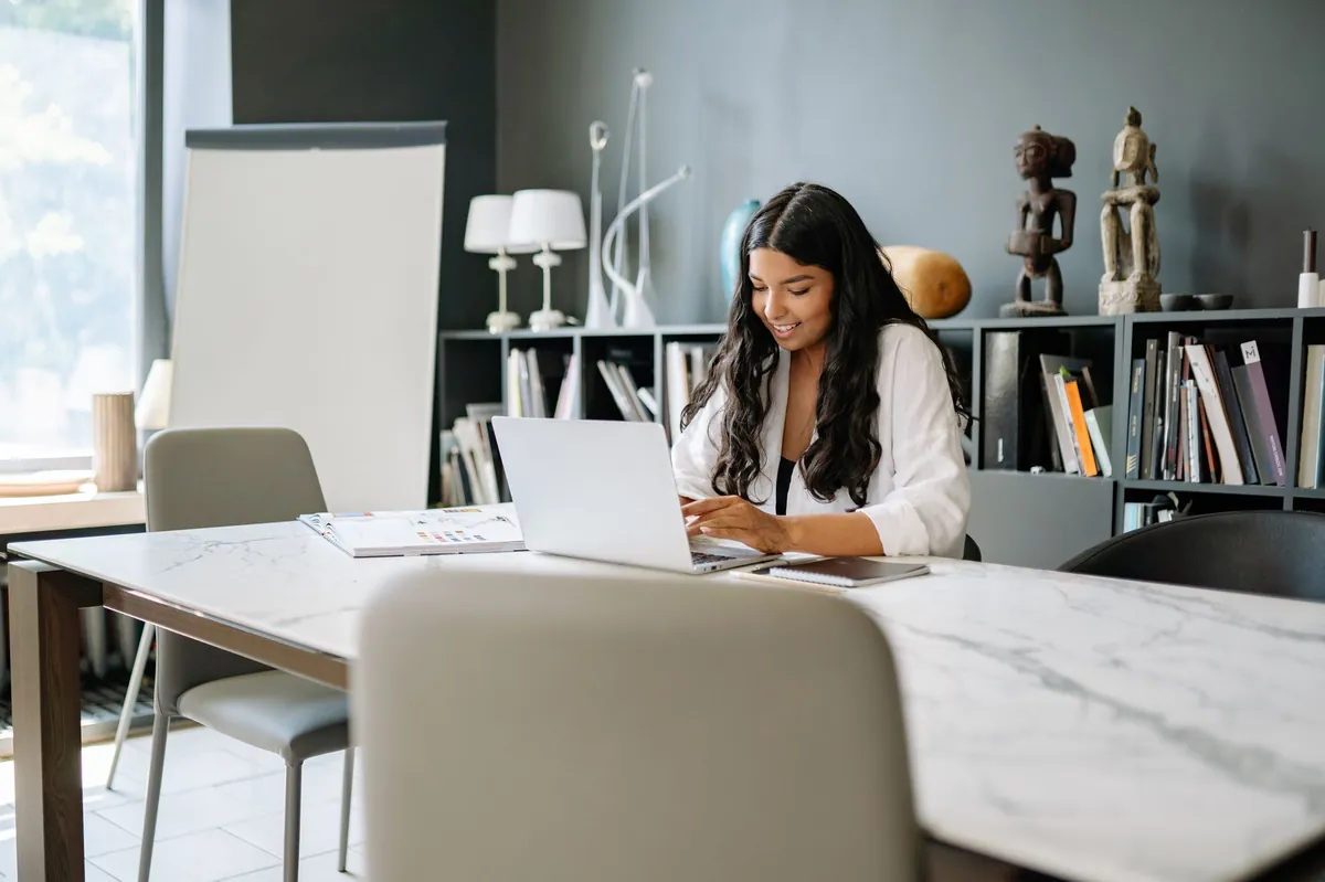 Professional working on a laptop at a marble conference table in a bright office