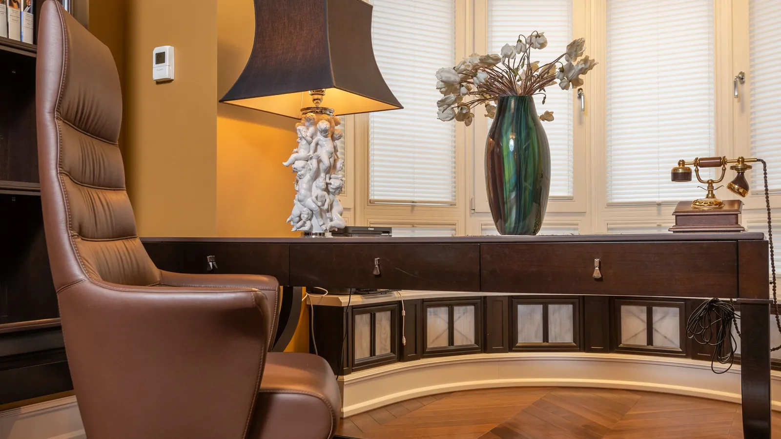 Warm study with a leather armchair, a carved desk and a tall lamp