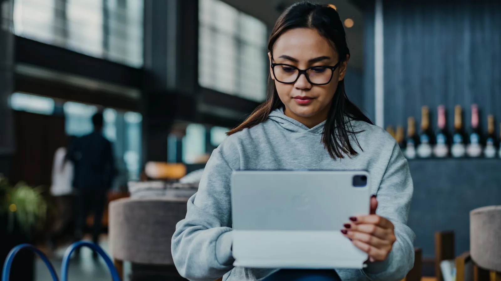 Reader in glasses using a tablet in a stylish lounge to research skin care questions