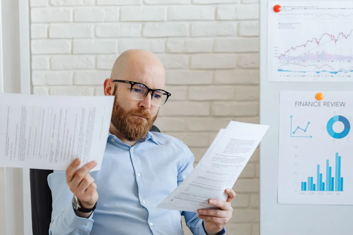 Business owner reading printed reports at a desk in a modern office