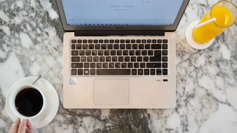 Overhead view of a laptop showing a search page on a marble table with coffee