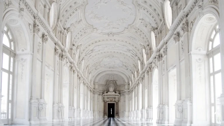 Long white palace gallery with arched windows and a polished marble floor