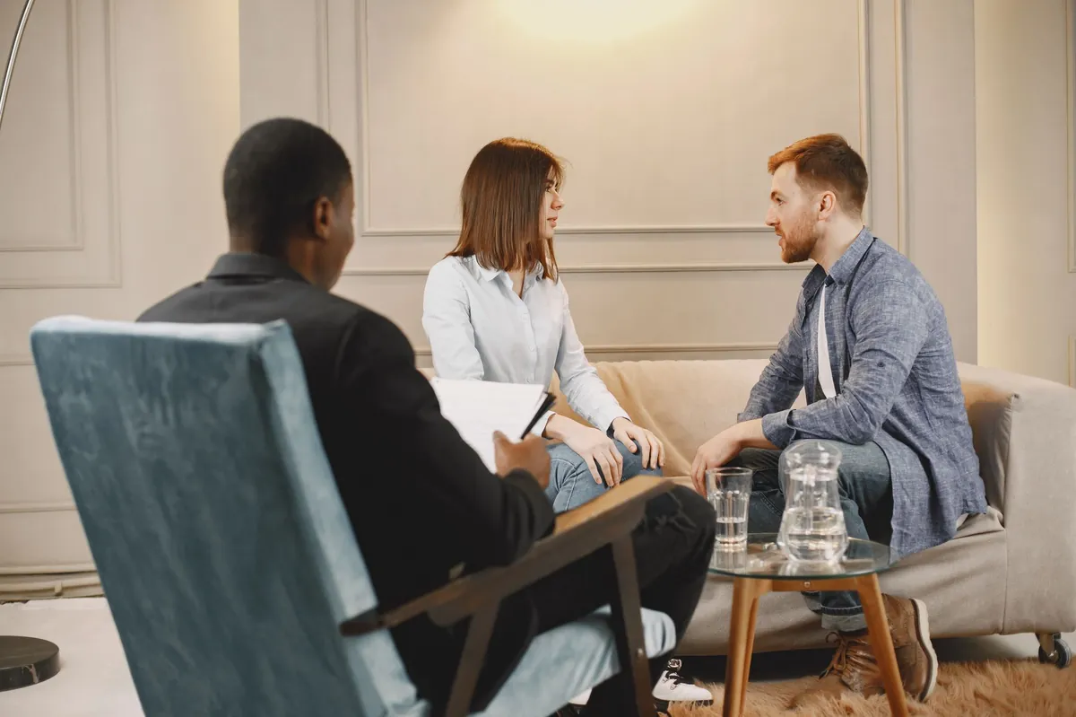 Three people in a calm conversation in a softly lit consultation lounge