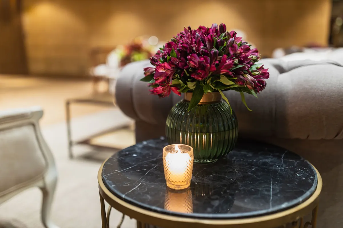 Boutique practice lounge with a black marble and brass side table, deep red flowers and a lit candle