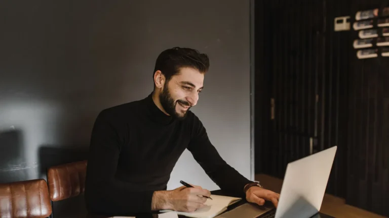 Smiling bearded professional reviewing site speed on a laptop in a contemporary office