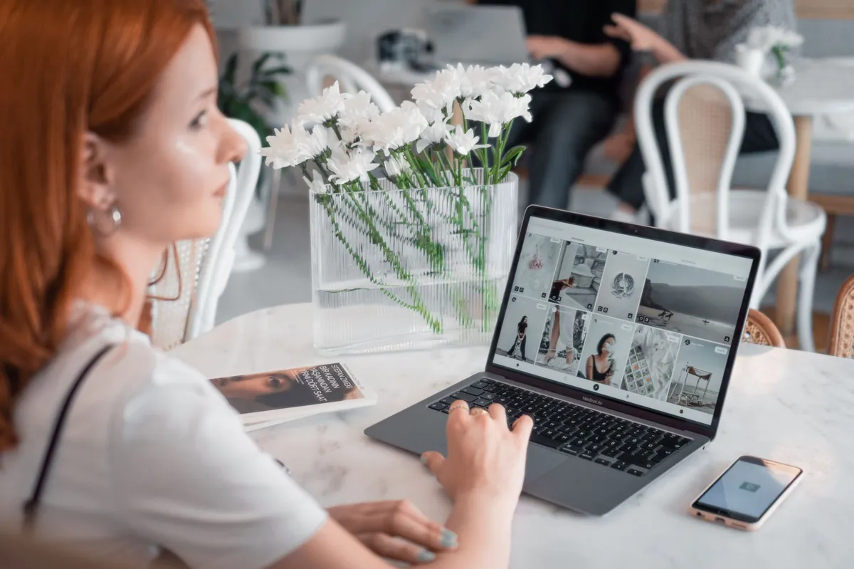 Woman with red hair working on a laptop in a bright cafe with fresh flowers