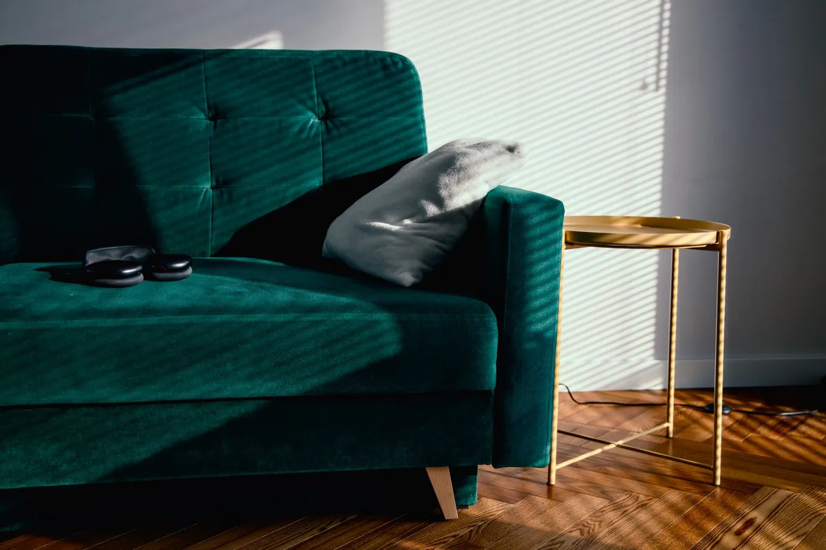 Emerald velvet sofa beside a brass side table in warm light
