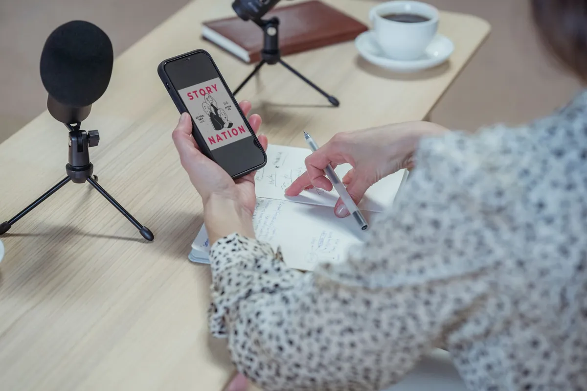 Creator browsing a phone at a desk set up with microphones for content production