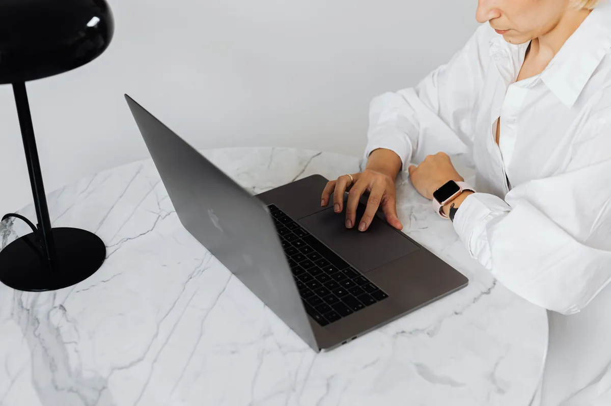 Professional typing on a laptop at a white marble desk