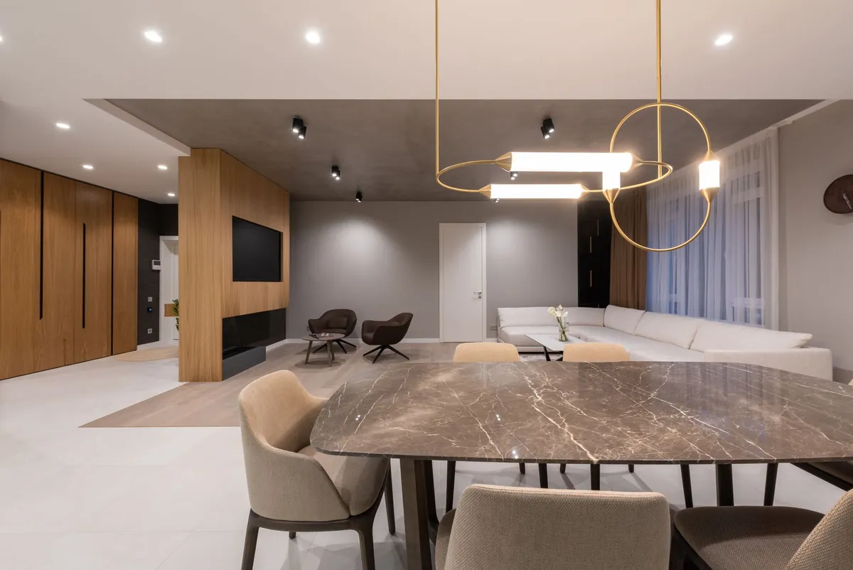 Modern conference room with a marble table, brass ring pendant lights and warm wood walls