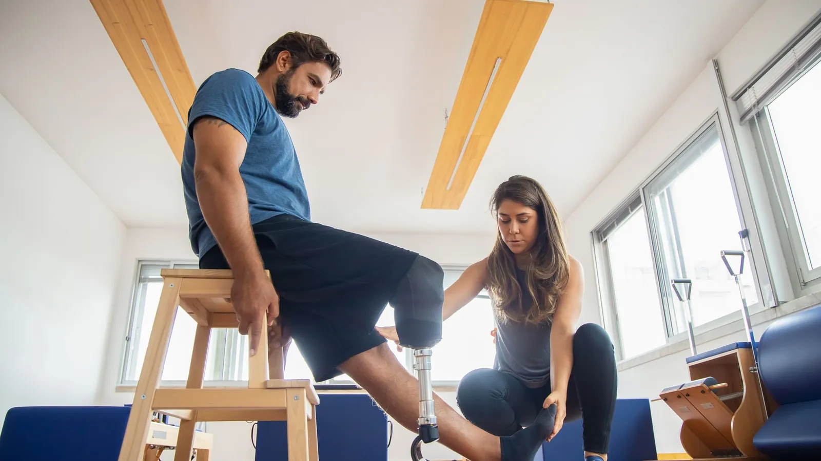 Physical therapist guiding a patient through a balance exercise in a bright, modern studio