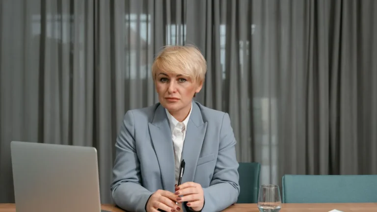 Practice owner in a gray blazer reviewing data on a laptop in a minimalist office
