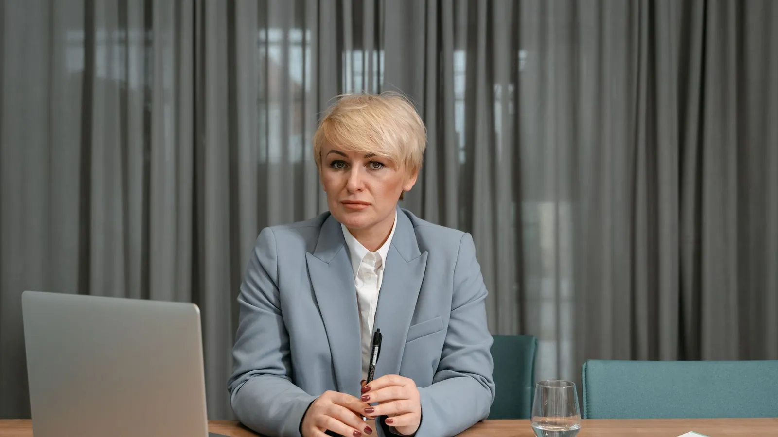 Practice owner in a gray blazer reviewing data on a laptop in a minimalist office